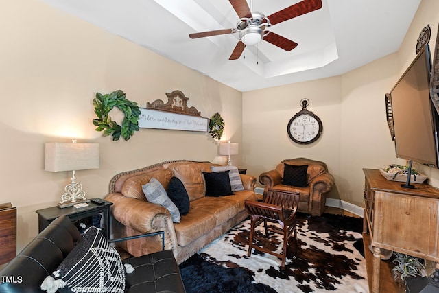 living room featuring hardwood / wood-style flooring, ceiling fan, and a raised ceiling