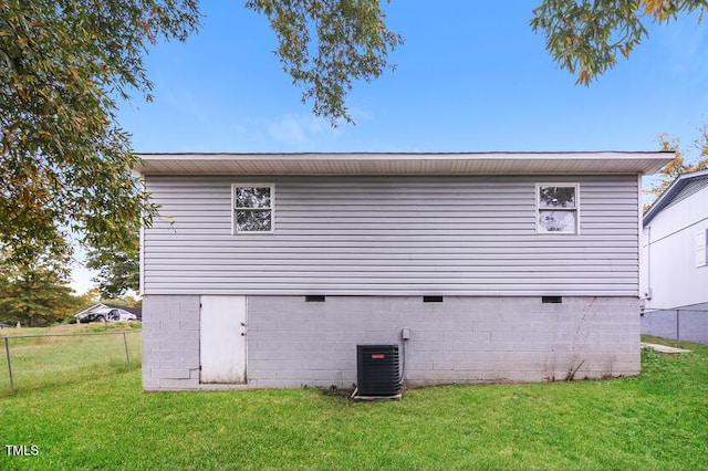 back of house with central air condition unit and a lawn