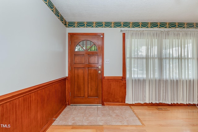 entryway with light hardwood / wood-style flooring, a textured ceiling, and a wealth of natural light