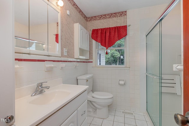 bathroom featuring tile patterned floors, toilet, tile walls, a stall shower, and vanity