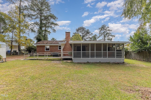 rear view of house with a chimney, a sunroom, fence, and a yard