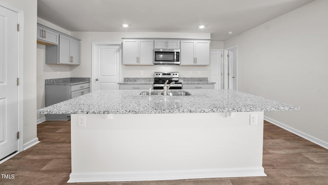 kitchen featuring a center island with sink, gray cabinets, dark hardwood / wood-style floors, and stainless steel appliances