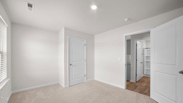 unfurnished bedroom featuring a closet and light colored carpet