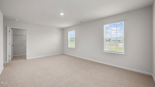 unfurnished bedroom featuring light colored carpet, a closet, and a spacious closet