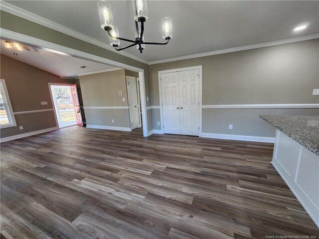 unfurnished dining area featuring ornamental molding, dark wood-type flooring, vaulted ceiling, and an inviting chandelier