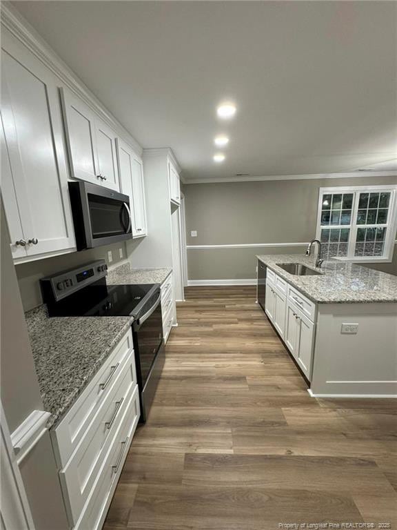 kitchen with white cabinets, appliances with stainless steel finishes, light stone countertops, and sink