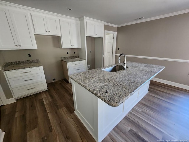 kitchen featuring a kitchen island with sink, sink, white cabinets, and stone countertops