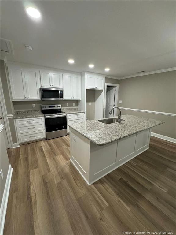 kitchen featuring appliances with stainless steel finishes, light stone counters, sink, a center island with sink, and white cabinets