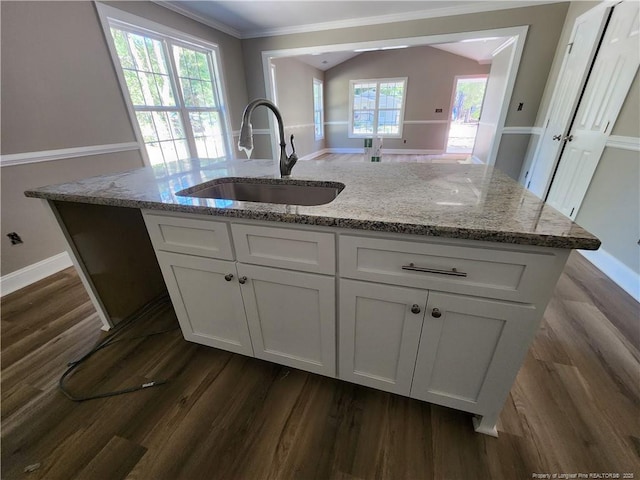 kitchen featuring light stone countertops, white cabinetry, a kitchen island with sink, and sink