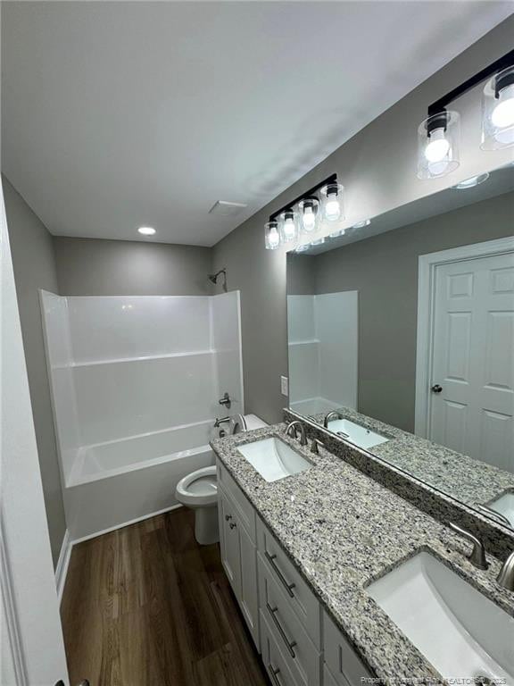 full bathroom with hardwood / wood-style floors, vanity, bathing tub / shower combination, and toilet