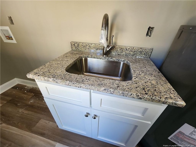 interior details with white cabinets, kitchen peninsula, light stone countertops, and sink