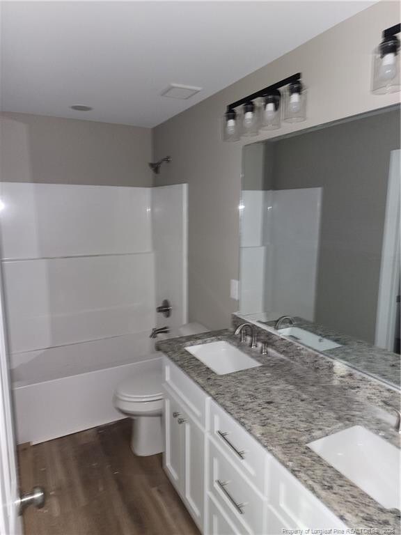 full bathroom featuring hardwood / wood-style floors, vanity, bathing tub / shower combination, and toilet