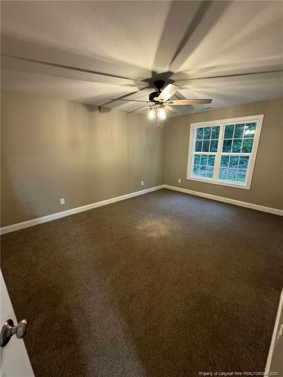 spare room featuring dark carpet and ceiling fan