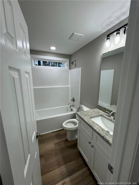 full bathroom featuring washtub / shower combination, hardwood / wood-style floors, vanity, and toilet