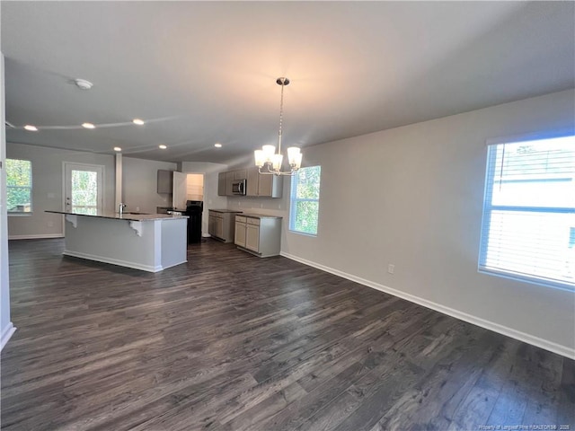 kitchen featuring pendant lighting, a center island with sink, a chandelier, dark hardwood / wood-style floors, and a breakfast bar area