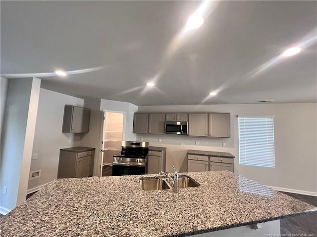 kitchen featuring appliances with stainless steel finishes, light stone counters, gray cabinetry, and sink