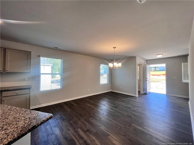 unfurnished dining area with a chandelier and dark hardwood / wood-style floors