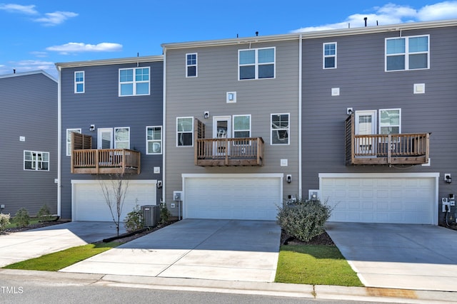 rear view of property with a balcony, central AC, and a garage