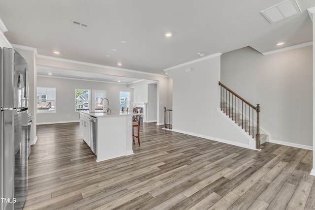 kitchen featuring a kitchen breakfast bar, white cabinets, wood-type flooring, and an island with sink