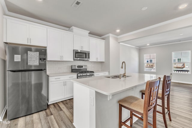 kitchen with white cabinetry, appliances with stainless steel finishes, sink, and a center island with sink