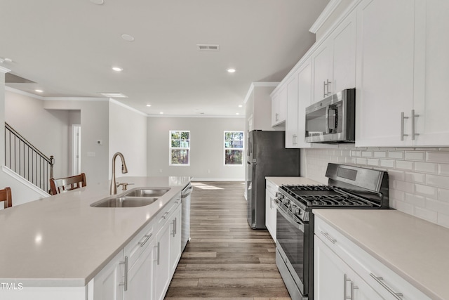 kitchen with light hardwood / wood-style flooring, an island with sink, stainless steel appliances, sink, and white cabinets