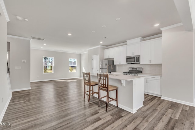 kitchen with white cabinetry, stainless steel appliances, crown molding, light hardwood / wood-style flooring, and a kitchen island with sink