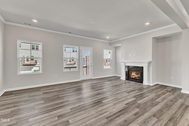 unfurnished living room featuring a wealth of natural light, crown molding, and light hardwood / wood-style flooring