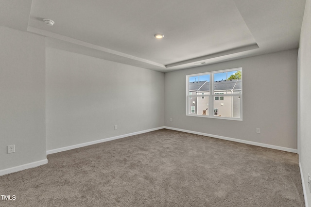 carpeted empty room featuring a tray ceiling