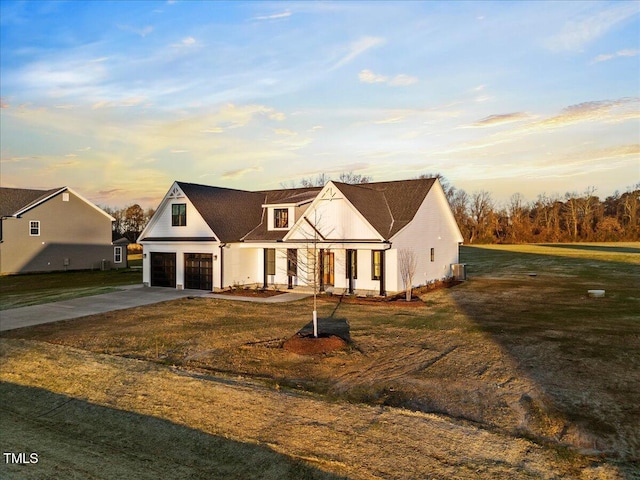 cape cod house with a garage, cooling unit, and a lawn