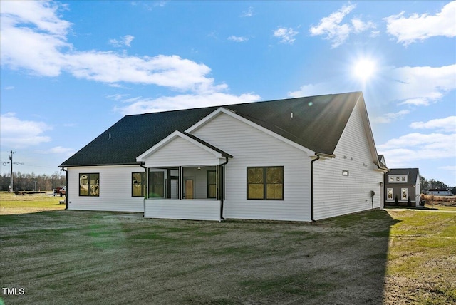 rear view of property featuring a lawn and a sunroom