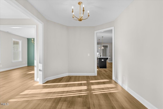 unfurnished dining area featuring hardwood / wood-style flooring, sink, and a chandelier