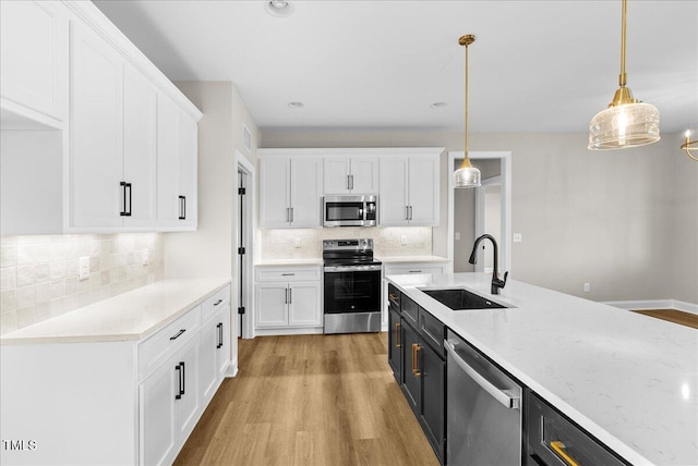 kitchen with white cabinetry, sink, hanging light fixtures, backsplash, and appliances with stainless steel finishes