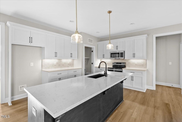 kitchen with white cabinets, stainless steel appliances, and a kitchen island with sink