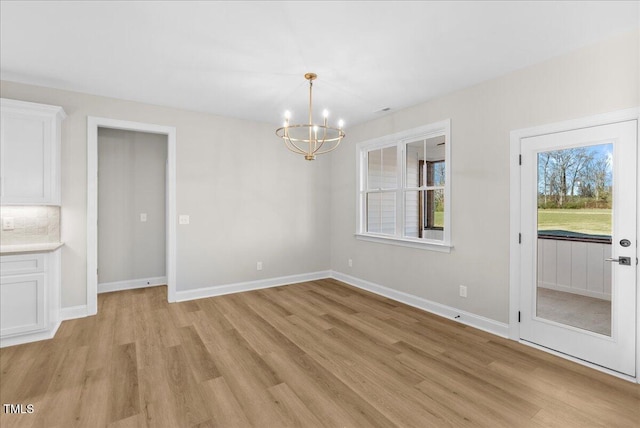 unfurnished dining area featuring light hardwood / wood-style flooring and a notable chandelier