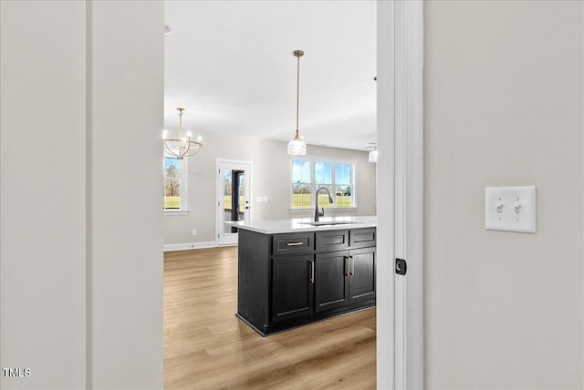 kitchen with a chandelier, sink, pendant lighting, and light hardwood / wood-style floors