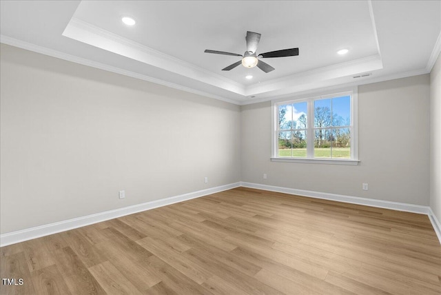 unfurnished room featuring a tray ceiling, ceiling fan, light hardwood / wood-style flooring, and ornamental molding