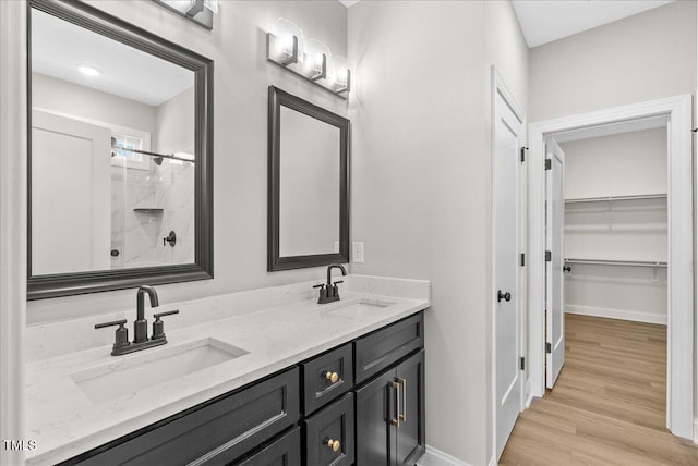 bathroom featuring hardwood / wood-style flooring, vanity, and walk in shower