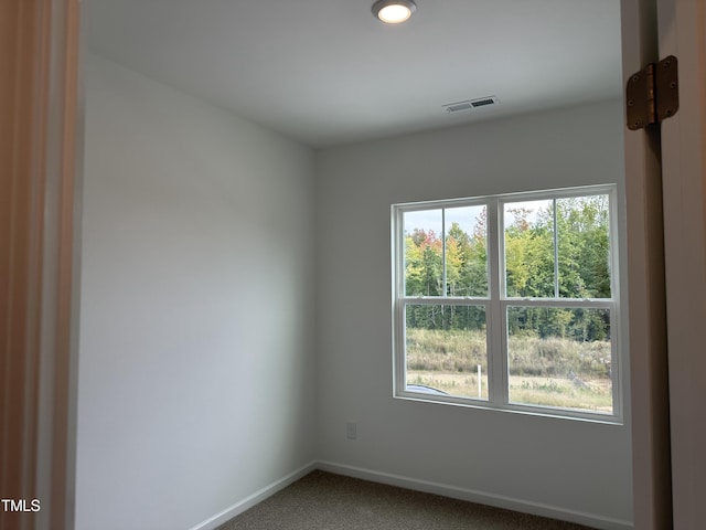 carpeted spare room featuring baseboards and visible vents