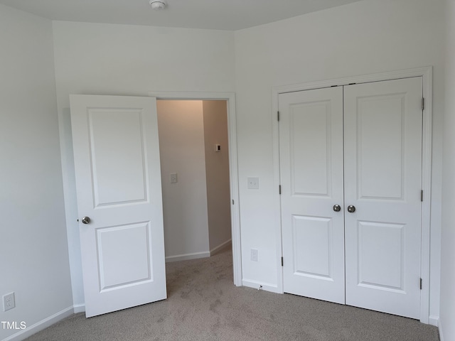 unfurnished bedroom with a closet and light colored carpet