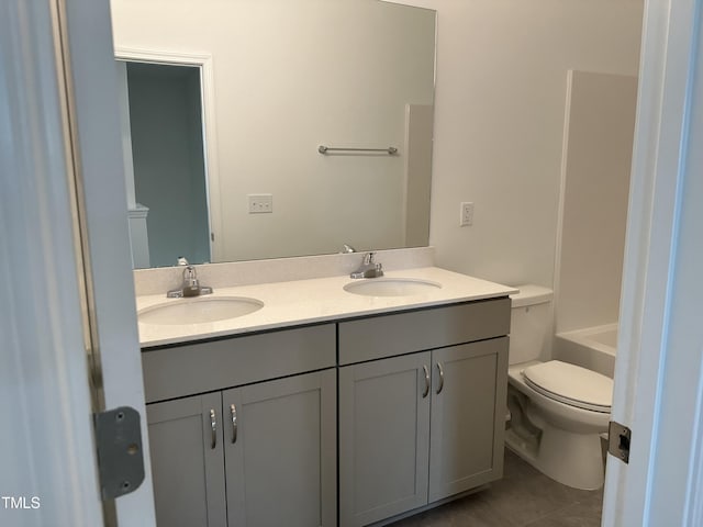 bathroom with double vanity, toilet, a sink, and tile patterned flooring