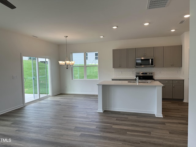 kitchen featuring appliances with stainless steel finishes, hanging light fixtures, dark wood-type flooring, and gray cabinetry