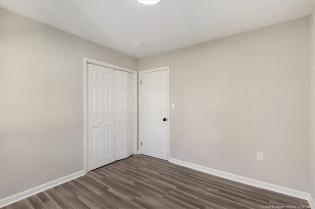 unfurnished bedroom featuring dark wood-type flooring and a closet