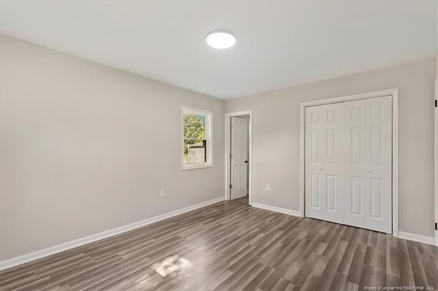 unfurnished bedroom with a closet and dark hardwood / wood-style floors