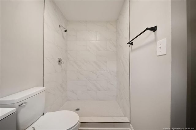 bathroom with toilet, tiled shower, and vanity