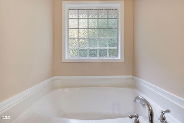 bathroom with a tub to relax in and plenty of natural light