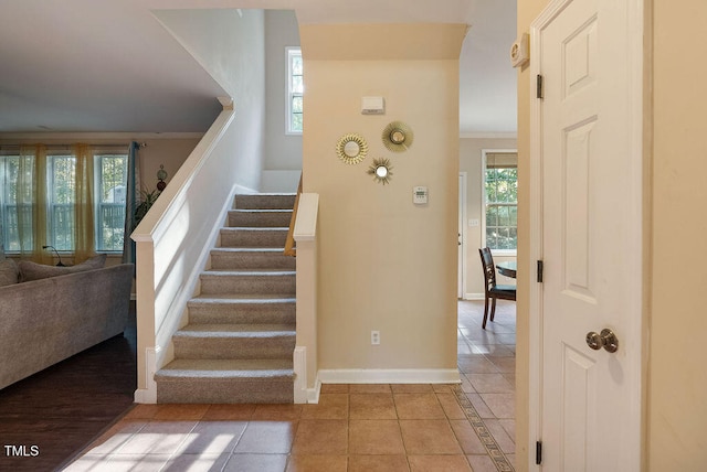 stairway featuring tile patterned floors and crown molding