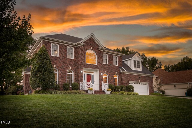 colonial inspired home featuring a garage and a lawn