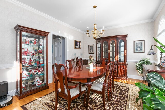 dining area with ornamental molding, an inviting chandelier, and light wood-type flooring