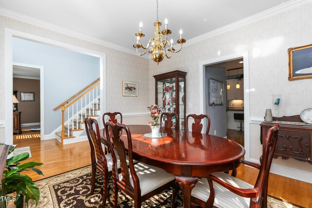 dining room with ornamental molding, hardwood / wood-style flooring, and a chandelier