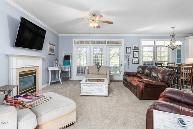 living room featuring light carpet, ornamental molding, and ceiling fan with notable chandelier